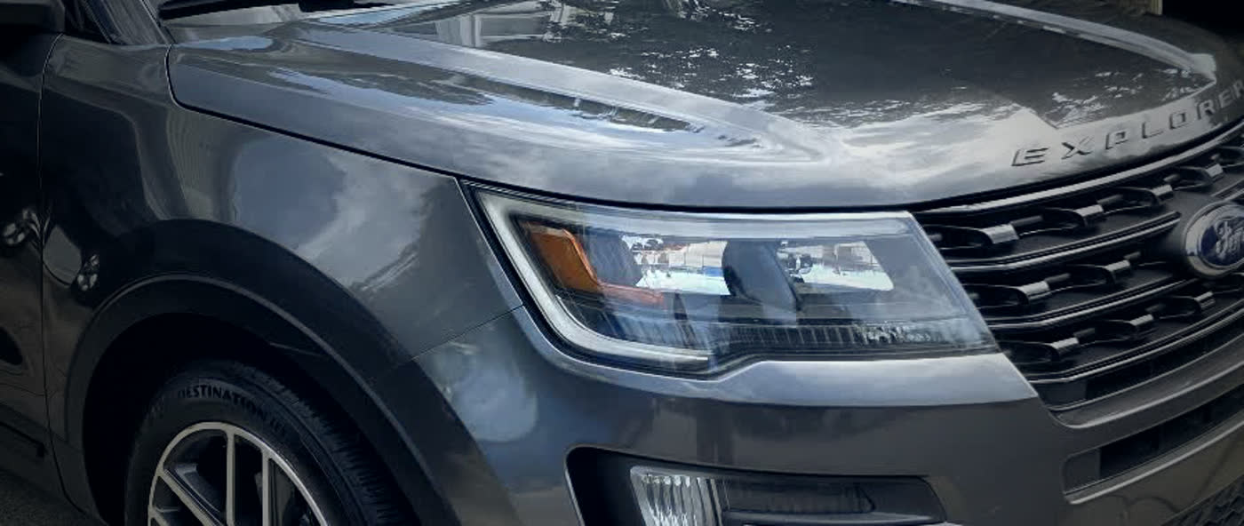 The hood of a detailed Ford Explorer reflecting the clouds above it